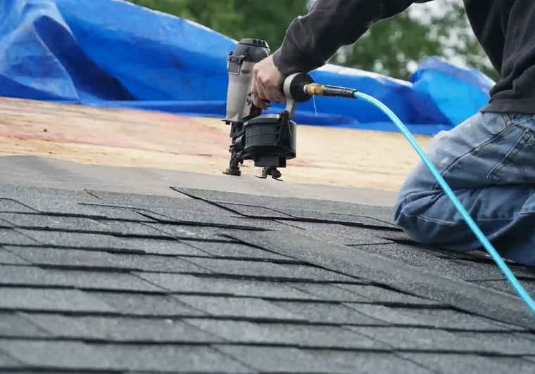 Emergency roof tarp being secured after storm damage